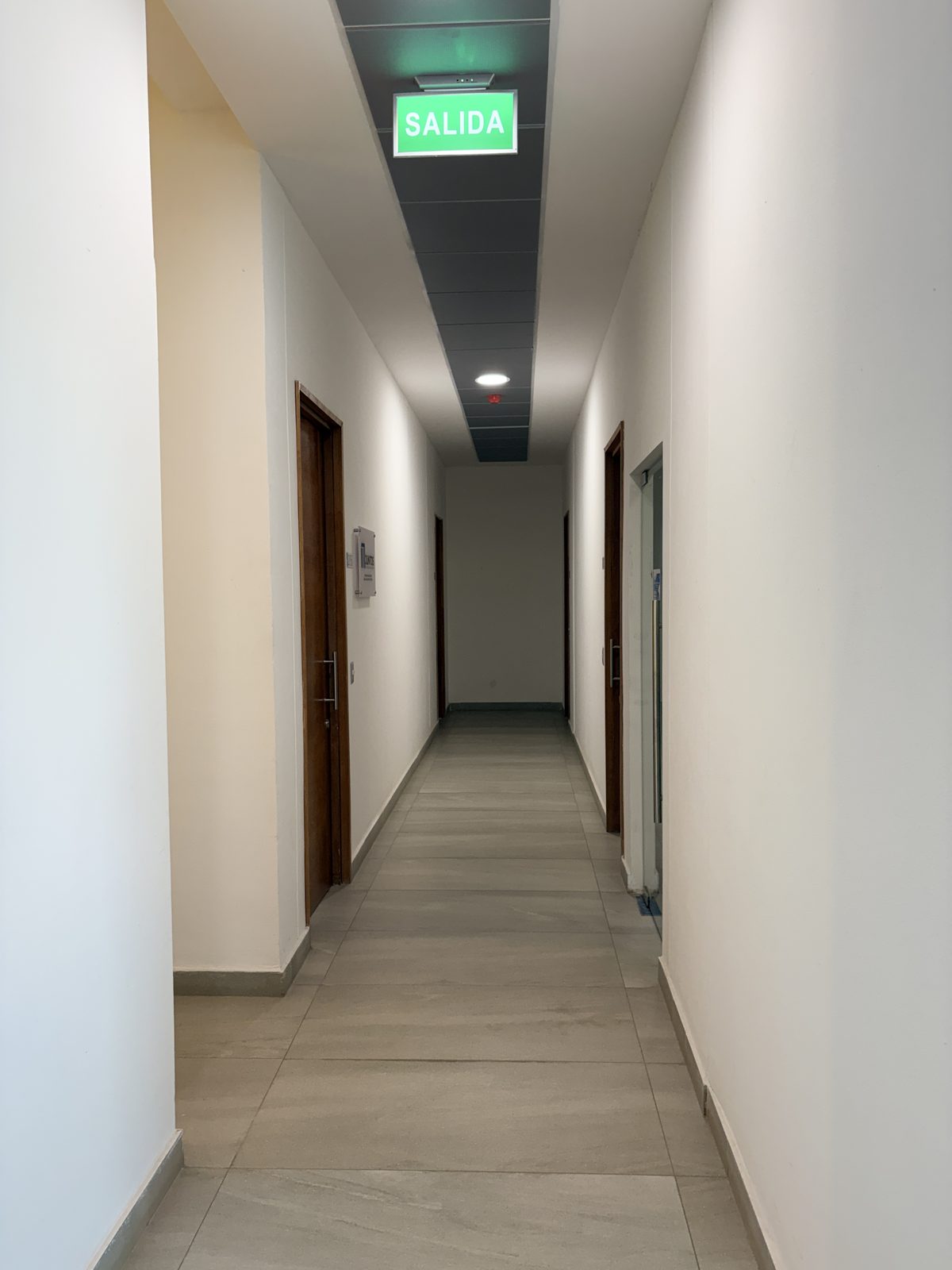 Pasillo de oficinas y consultas habilitadas, con porcelanato e iluminación