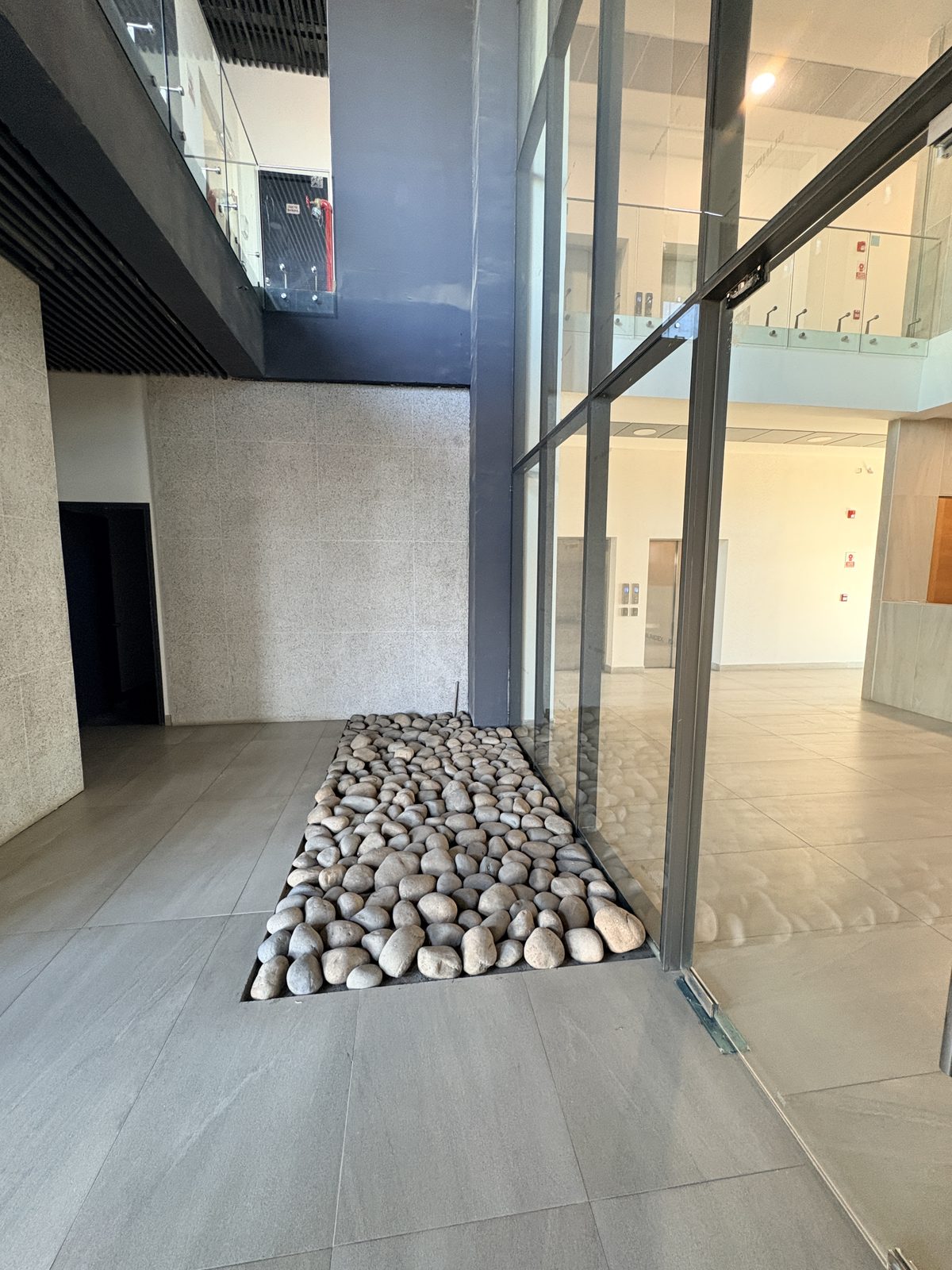 Hall de acceso con jardín de piedras y doble altura